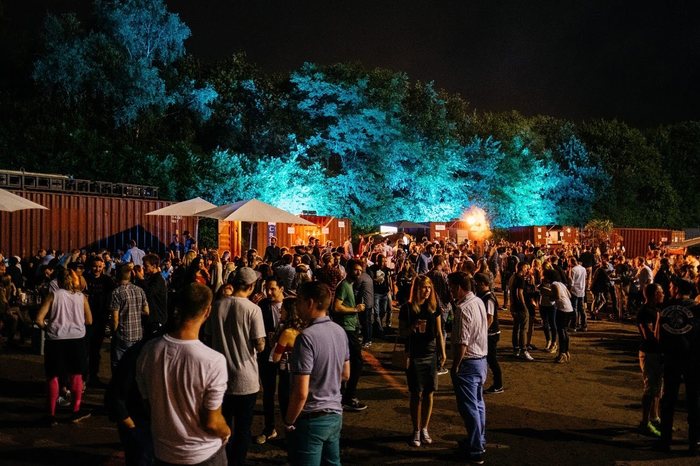 Festivalpublikum bei Nacht vor beleuchteten Bäumen auf dem Areal der MIGNON Trabrennbahn