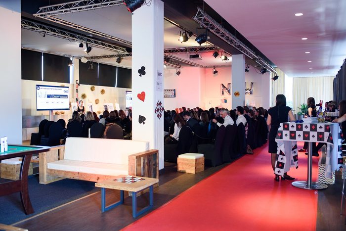 Konferenz mit rotem Teppich, Bühne und Lounge-Möbeln in der Eventhalle der MIGNON Trabrennbahn