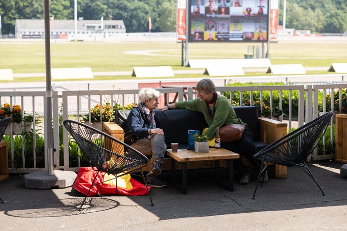 Gäste auf der Lounge-Terrasse der MIGNON Trabrennbahn mit Blick auf das Infield