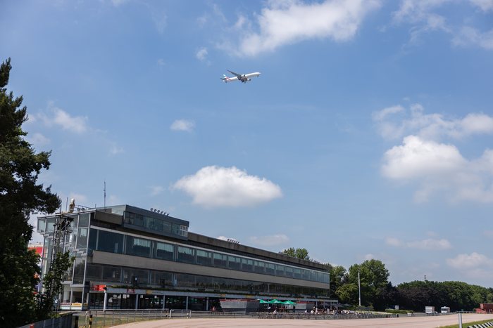 Tribünengebäude der MIGNON Trabrennbahn an einem Sommertag mit Flugzeug am Himmel