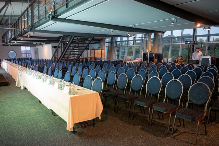 Festlich eingedeckte lange Tafel und Reihenbestuhlung in der Hafen Location Hamburg