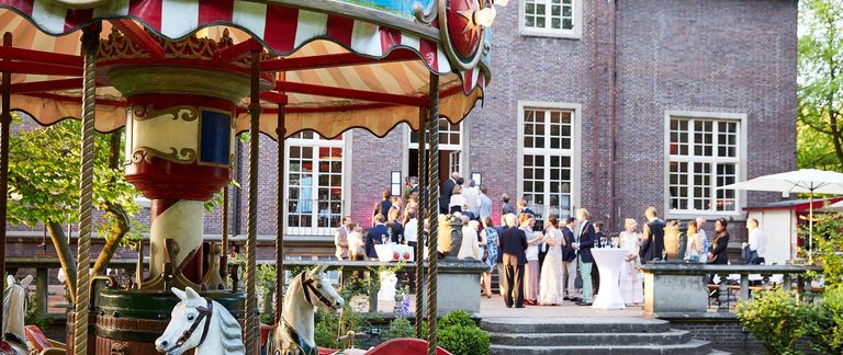Sommerfest mit nostalgischem Karussell und Gästen im Garten der Villa Mignon