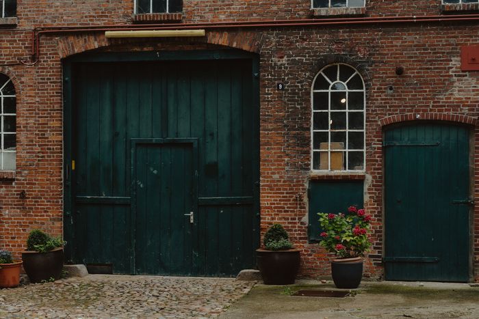 Backsteinfassade der historischen Scheune der Stadtfarm mit grünen Toren