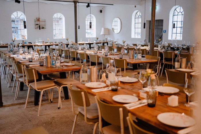 Lange eingedeckte Tafeln im hellen Saal der Stadtfarm für Feiern und Hochzeiten